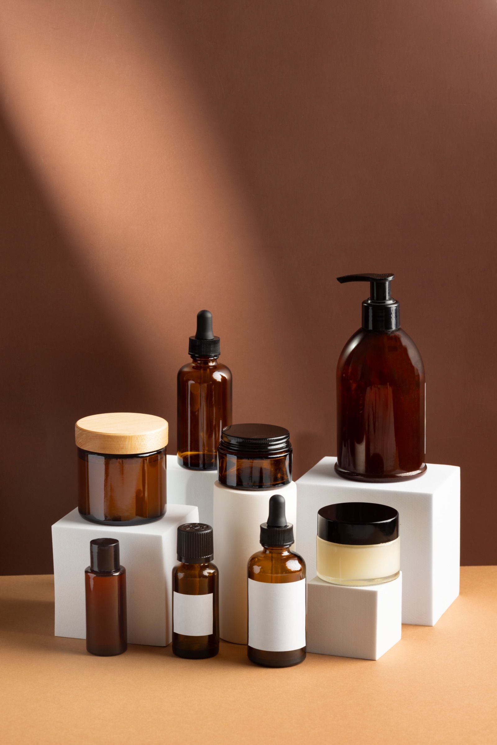 Amber glass skincare bottles and jars on white display blocks